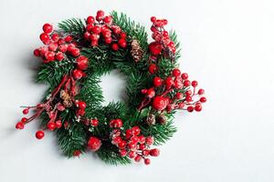 Christmas decorative wreath of holly, ivy, mistletoe, cedar and leyland leaf sprigs with red berries over white background. photo