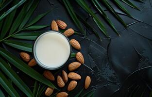 AI generated Almond milk in glass and almonds with green leaves on black background photo