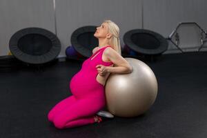 Pregnant woman exercise with fitness bal in gym photo