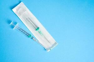Two plastic disposable medical syringes open and package lie on blue background. photo