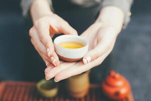 Woman offers hot tea in a vintage ceramic cup. photo