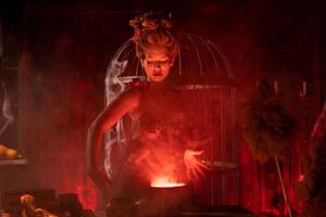 Halloween Witch with cauldron. Beautiful young woman conjuring, making witchcraft photo