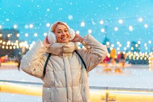 Wintertime. Christmas holiday evening, woman standing outside and smile. Christmas illumination and decoration background. Winter holiday season. photo