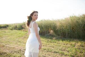 Beautiful caucasian girl walking on the field. Summer time day photo