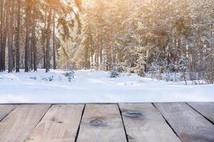 Beautiful winter scene. View from home terrace at magical snowy forest in morning with wooden planks floor, sun flare photo