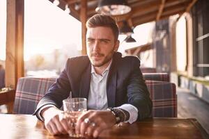 Handsome young businessman sitting in a summer outdoor cafe on the background of the evening sunset at the negotiating table photo