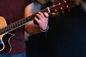 masculino músico jugando acústico guitarra. guitarrista obras de teatro clásico guitarra en etapa en concierto cerca arriba foto