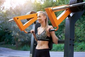 Sportive female training exercise machine outdoor gym summer park photo