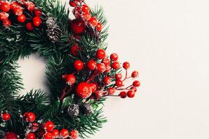 Christmas decorative wreath of holly, ivy, mistletoe, cedar and leyland leaf sprigs with red berries over white background. photo