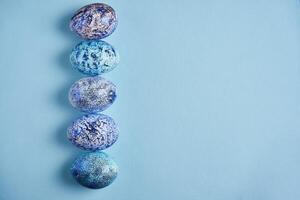 Beautiful blue easter eggs lie in a row on a blue paper background. photo