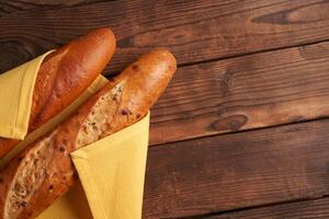 two crispy french baguettes lie on an old wooden table with free space for text photo