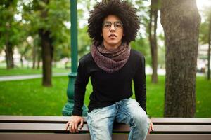 joven afro americano joven empresario o estudiante vistiendo negro suéter tipo con cuello de tortuga suéter y bufanda y teniendo Rizado oscuro cabello. concepto de elegante y de moda Mira foto