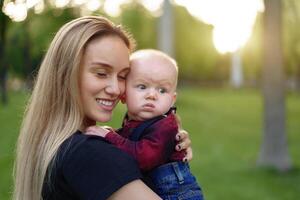 Beautiful young mother walks with her little son in a summer park photo