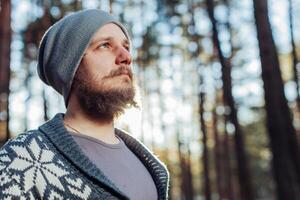 un joven hombre con un barba camina en un pino bosque. retrato de un brutal barbado hombre otoño bosque foto