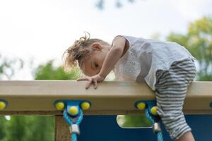 Little Caucasian girl plays on playground climbs stairs upstairs. photo