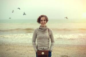 glamourous portrait of the young beautiful woman  in leather boots on the bank of a beach photo