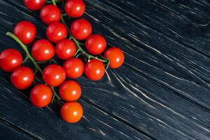 Cereza Tomates en el oscuro negro de madera mesa foto