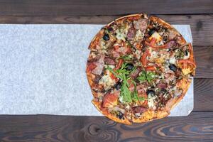 Appetizing pizza with smoked sausages bacon meat tomato cheese arugula photo