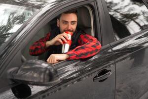 Young attractive Caucasian man sits at the wheel of his car sunny winter day. photo