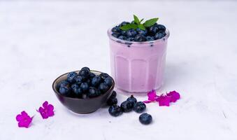 Tasty fresh blueberry yoghurt shake dessert in glass standing on white table background. photo