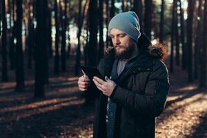 cerca arriba retrato de adulto masculino caminante utilizando digital lengüeta y mirando para ubicación durante caminata en naturaleza. hombre en caminata utilizando digital tableta para navegación. foto