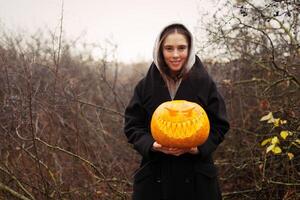 joven sonriente mujer participación el Víspera de Todos los Santos calabaza foto