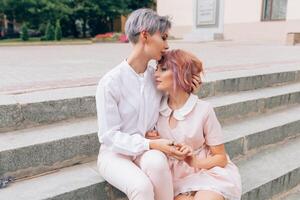 Two hugging girls sitting on the stairs in the city photo