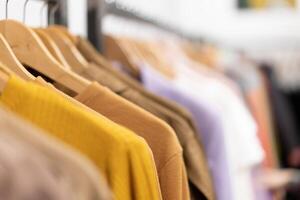 Multi colored clothing shirts hang on hangers in a shop background. A variety of clothes  hanging in the wardrobe. photo