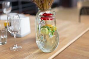 sano comida y bebidas agua en vaso jarra con limón y menta en de madera mesa en café foto