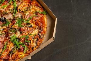 Appetizing pizza with smoked sausages bacon meat tomato cheese arugula photo