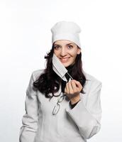 a woman in a white lab coat holding a mask photo