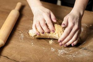 manos laminación masa para pan de jengibre en el de madera mesa foto