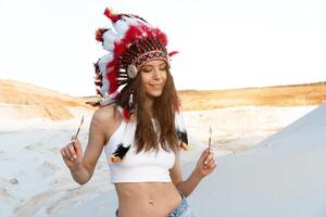 un hermosa joven caucásico niña en un blanco parte superior en su cabeza es vistiendo un indio sombrero. cucaracha es en el desierto. contento fiesta humor. foto