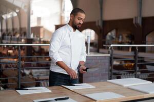 Handsome young chef African ethnicity lays knives on table in front of a culinary master class. photo