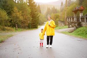 Rainy day Mother and little daughter walking after rain dressed yellow raincoat photo