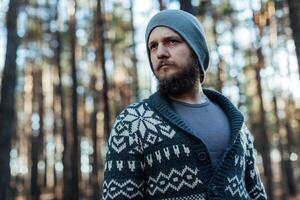 a young man with a beard walks in a pine forest. Portrait of a brutal bearded man Autumn forest photo