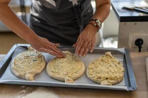 culinario Maestro clase. de cerca de personas manos preparando khachapuri. tradicional georgiano queso un pan. georgiano comida foto