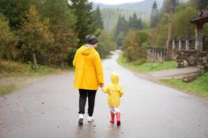 Rainy day Mother and little daughter walking after rain dressed yellow raincoat photo