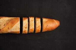 one sliced french baguettes lie on an old wooden table with free space for text photo