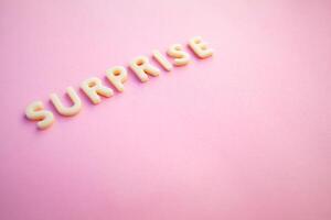 Surprise word written in voluminous white letters on a beautiful pink background. photo