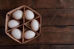 blanco pollo huevos mentira en redondo de madera cesta cuales soportes en un oscuro de madera mesa. foto