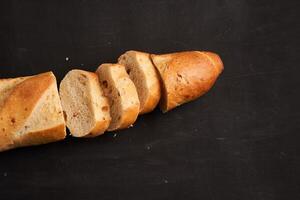 one sliced french baguettes lie on an old wooden table with free space for text photo