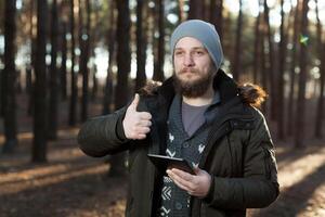 Portrait of adult man walking in the pine forest with digital tablet. photo