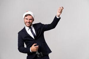 Young handsome caucasian guy in business suit and Santa hats stands on white background in studio and Plays on an imaginary guitar. photo