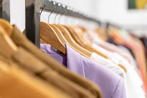 Multi colored clothing shirts hang on hangers in a shop background. A variety of clothes  hanging in the wardrobe. photo