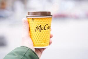 Ucrania, Kiev febrero 2021 irreconocible hombre participación amarillo papel taza con café McCafe en mano foto
