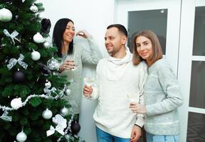 Two young women decorate the Christmas tree, preparing for the New Year's celebration photo