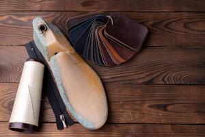 Leather samples for shoes and plastic shoe last on dark wooden table. photo