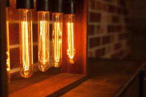 Light bulb lamp on dark red brick background with hotspot close up loft photo