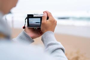 Traveller make photo holding mirrorless camera in hand